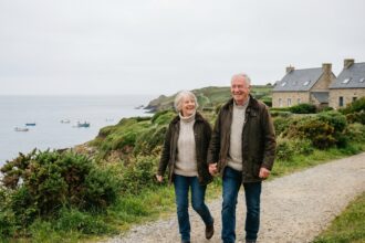 Couple retraité souriant se promenant en bord de mer en Morbihan